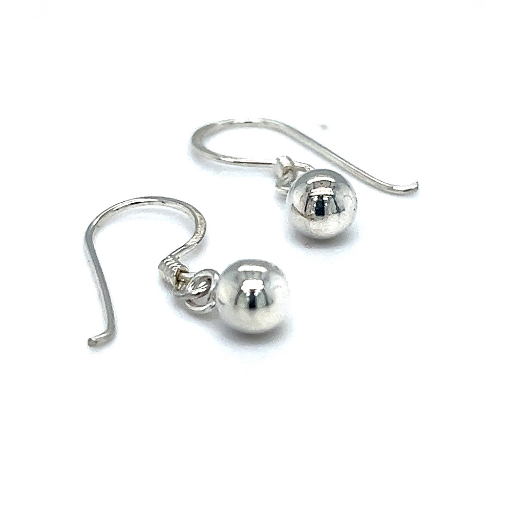 
                  
                    A pair of Simple Dangling Ball Earrings by Super Silver, exuding understated glamour in a chic style, on a white background.
                  
                
