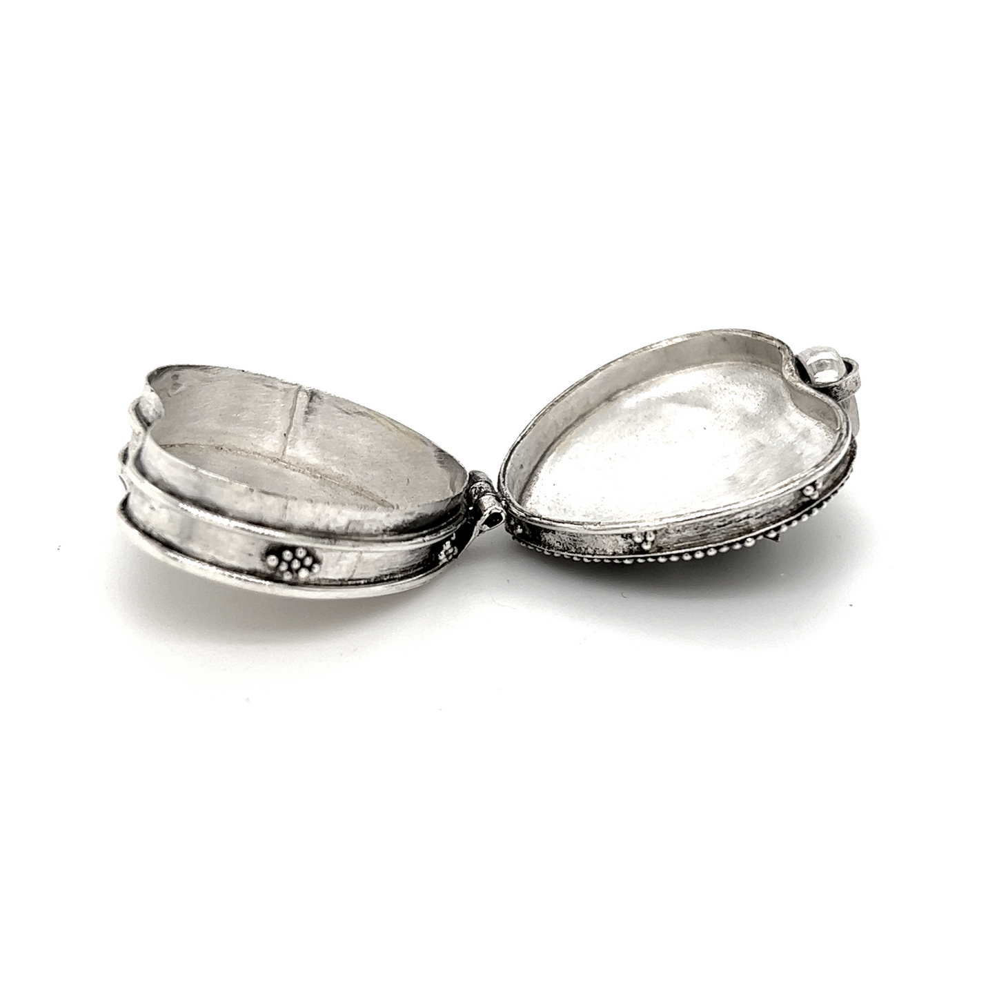 
                  
                    A Bali Heart Shaped Prayer Box Pendant with an open lid on a white surface by Super Silver.
                  
                
