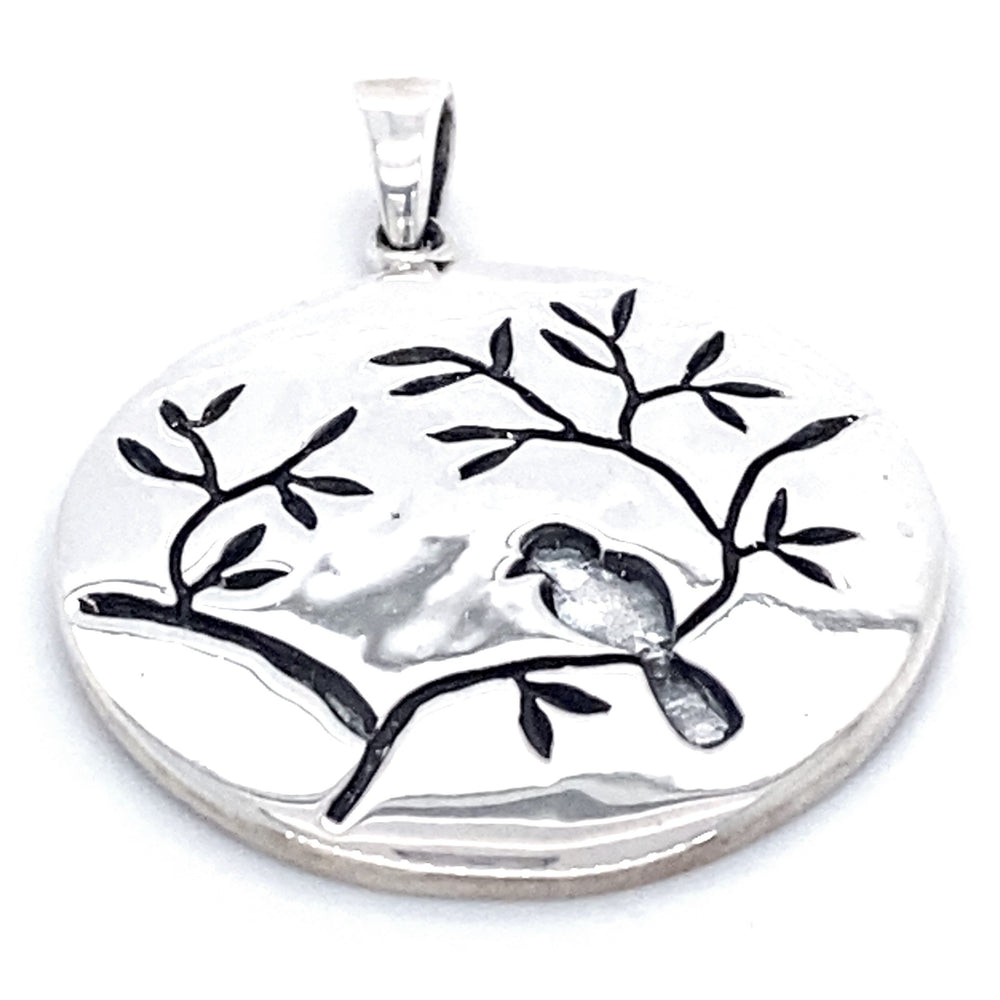 A Large Circle Nature Pendant with Bird featuring a carved bird perched on a branch with delicate cherry blossoms.