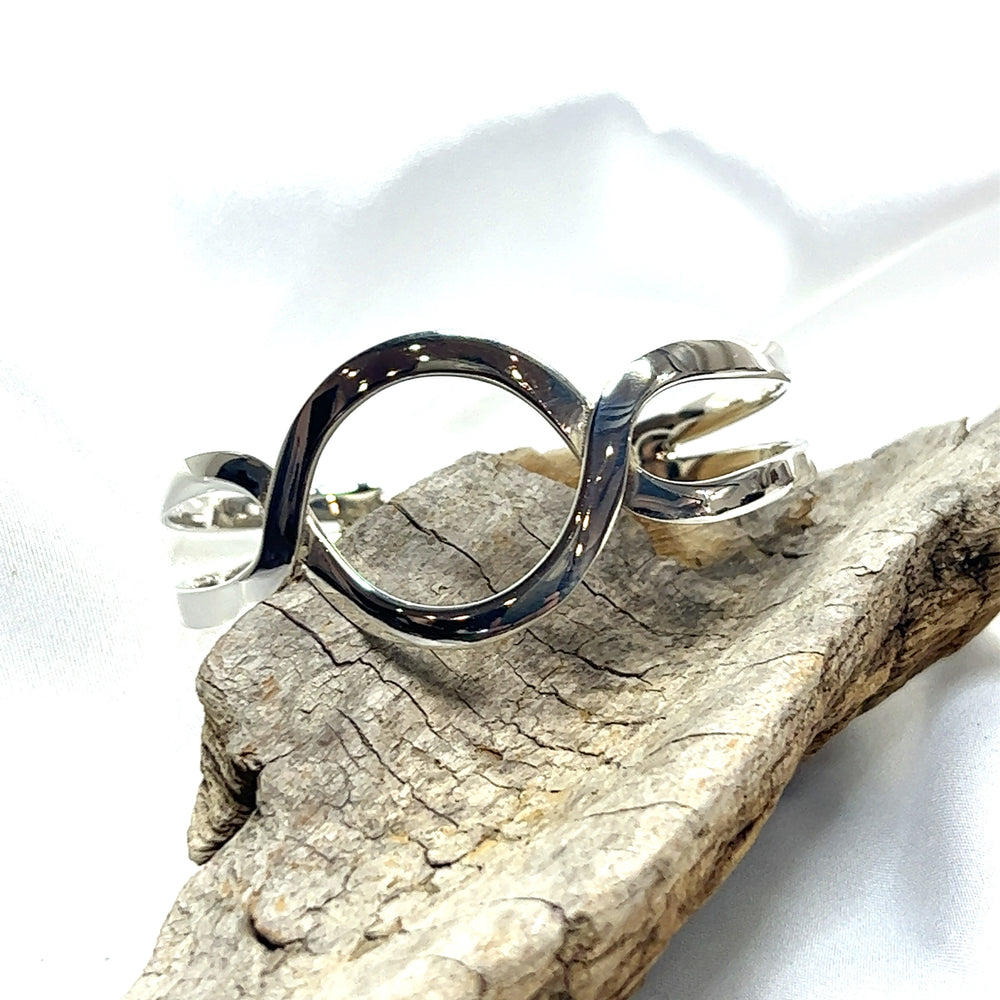 A Super Silver Trendy Twisted Cuff with Circle Design on a piece of wood with boho chic vibes.
