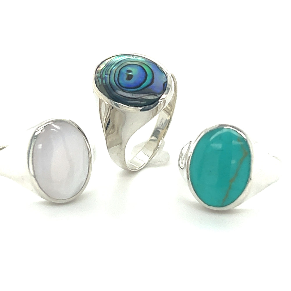 A minimalist Sleek Oval Inlaid Stone Signet Ring with a silver base and a blue stone.