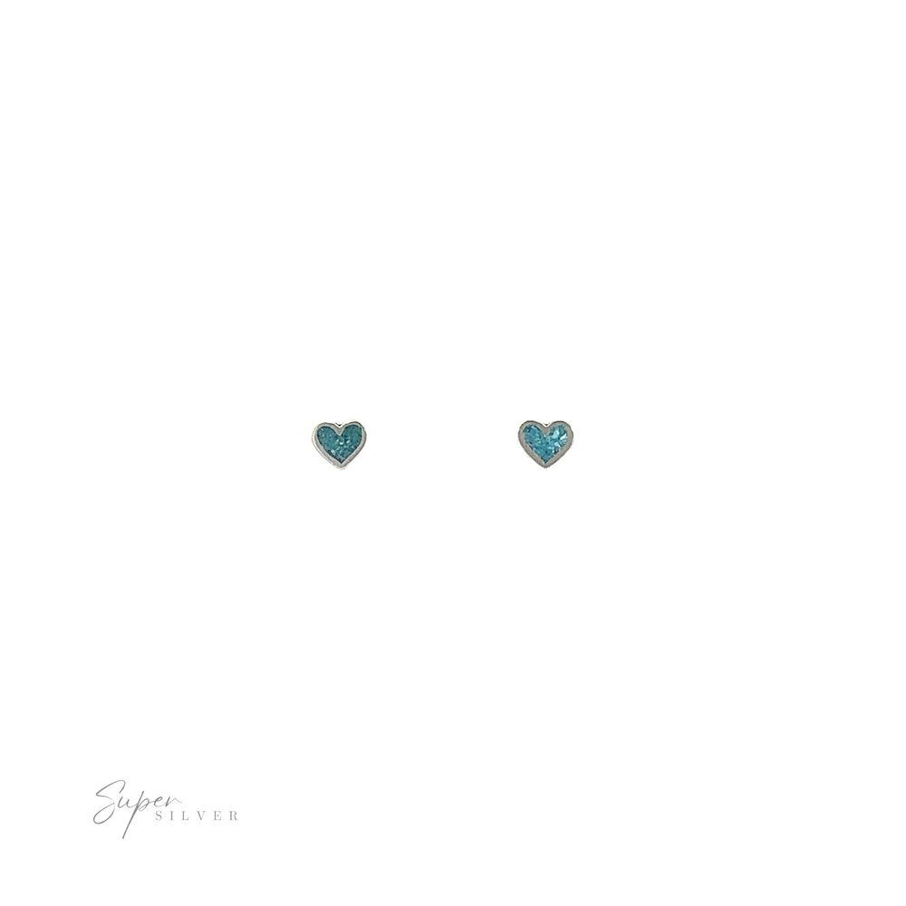 
                  
                    A pair of Tiny Turquoise Heart Studs with inlaid turquoise on a white background.
                  
                