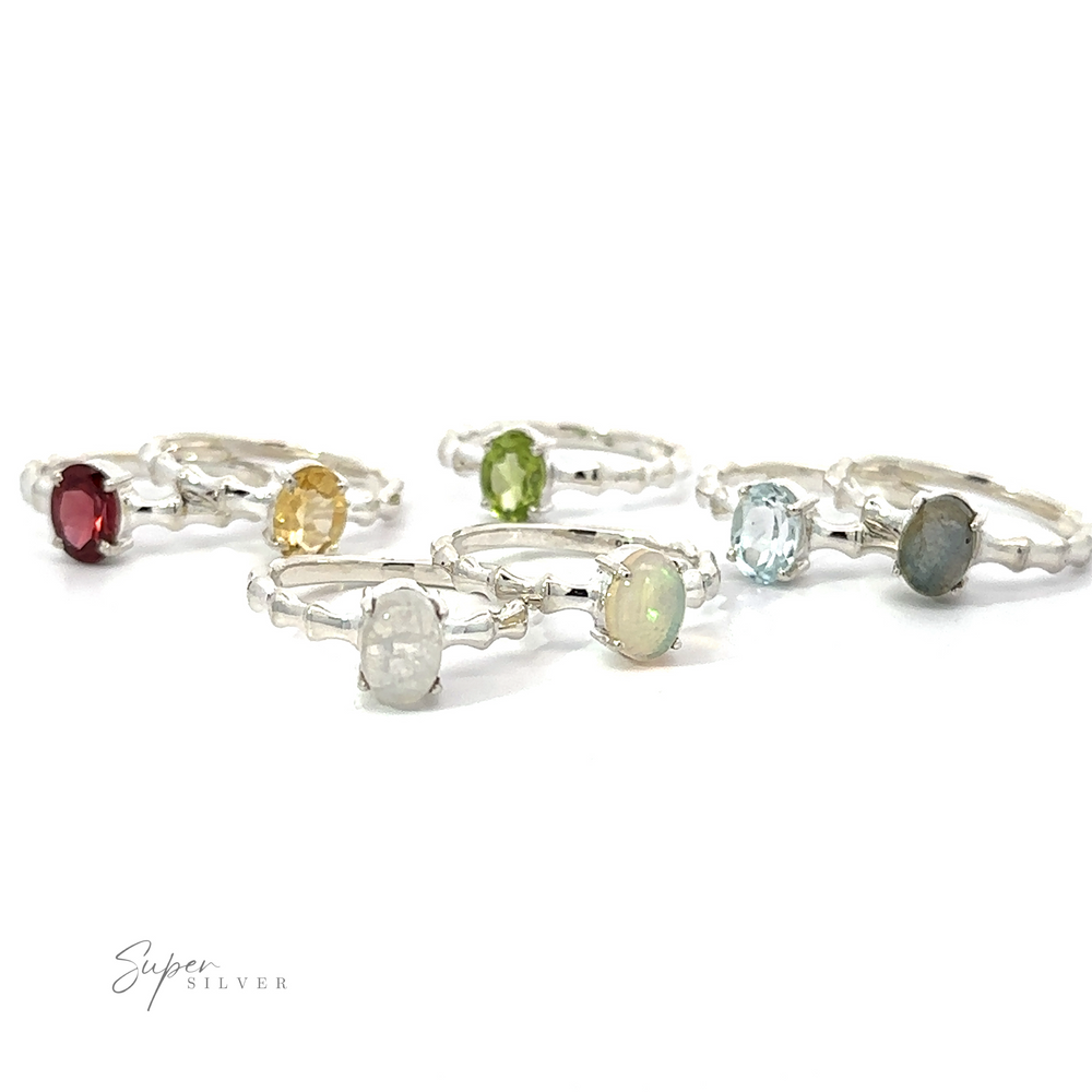 
                  
                    A collection of Pronged Oval Gemstone Rings with Textured Bands, including Blue Topaz, on a white background.
                  
                