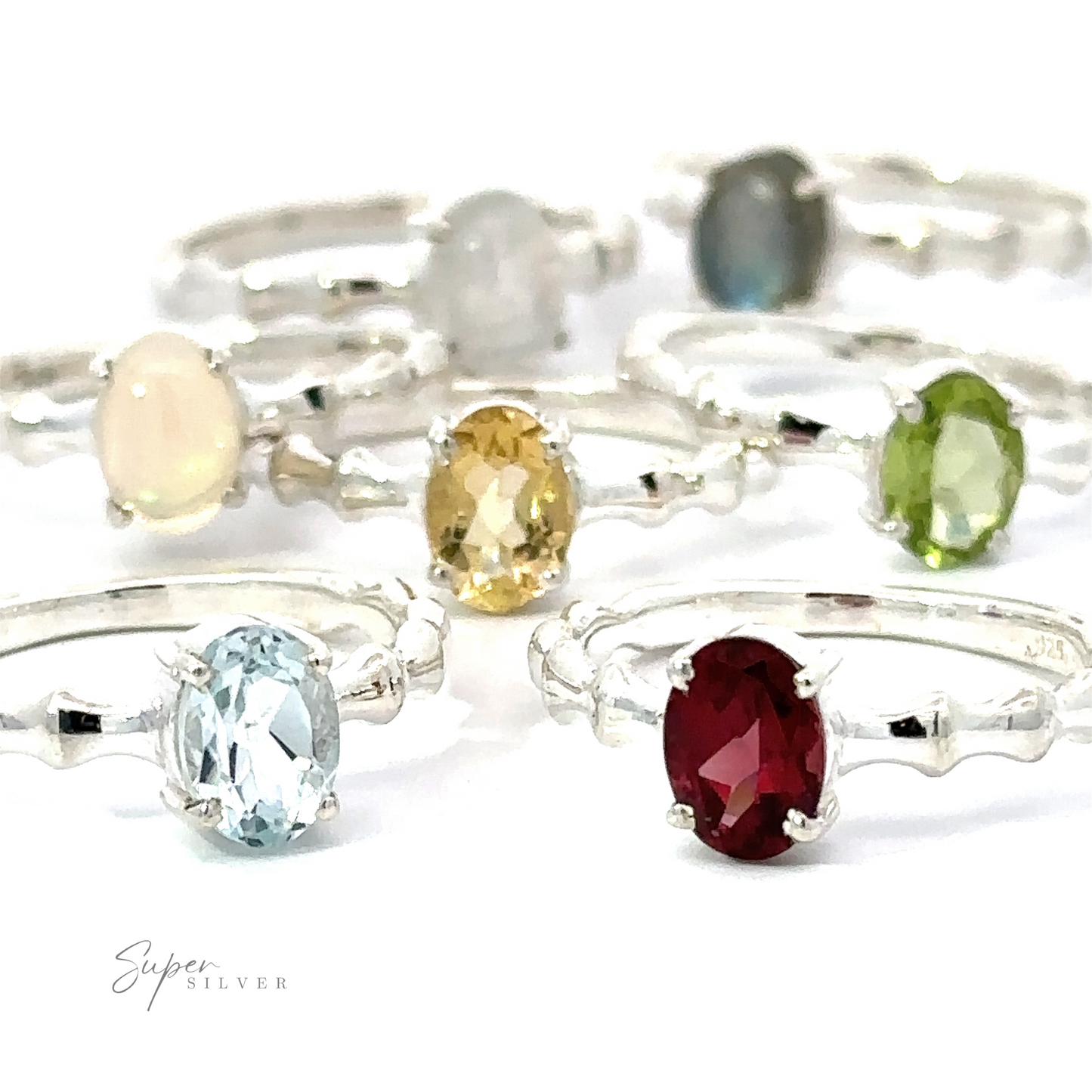 An assortment of Pronged Oval Gemstone Rings with Textured Bands, including Blue Topaz, on a white background.