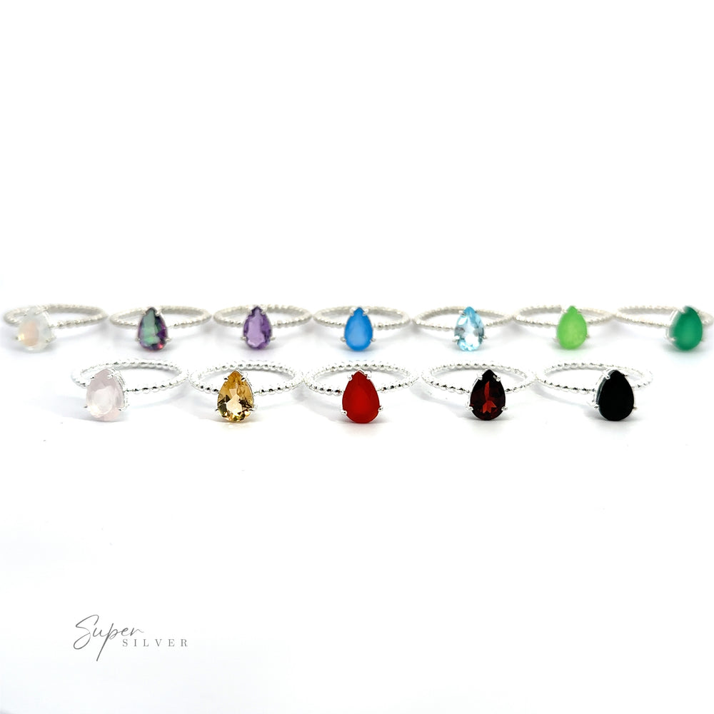 
                  
                    A collection of Vibrant Teardrop Gemstone Rings with Beaded Bands arranged in a line on a white background.
                  
                