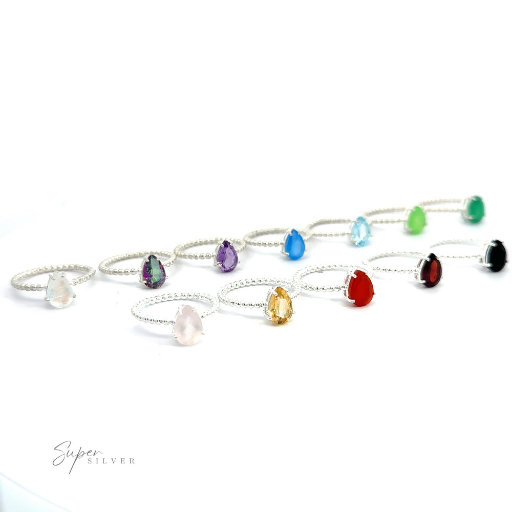 A collection of Vibrant Teardrop Gemstone Rings with Beaded Bands displayed on a white background.