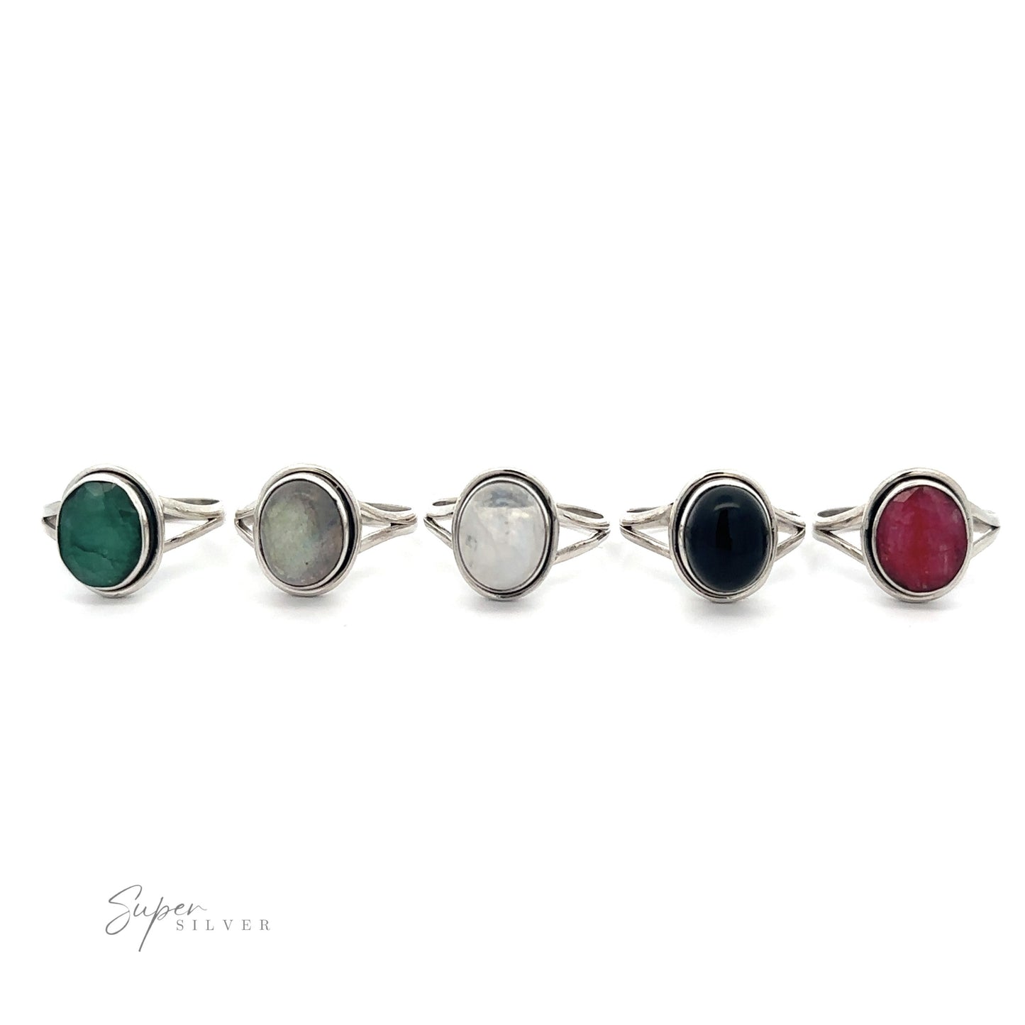A collection of five Oval Split Shank Stone Rings with various colored gemstones including moonstone and emerald, displayed in a line against a white background.