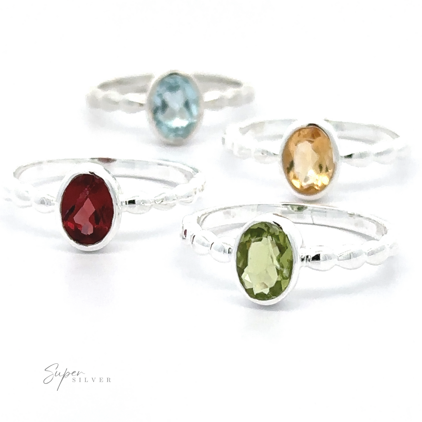 
                  
                    Four sterling silver Oval Gemstone Rings with Beaded Bands, each with a different colored oval gemstone (red, green, blue, yellow), arranged against a white background.
                  
                