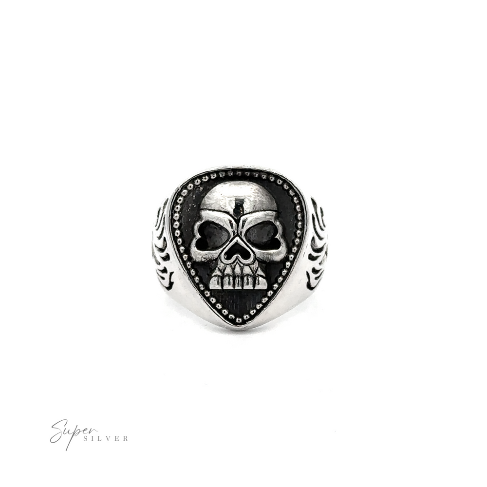 A Guitar Pick Skull Ring featuring a raised skull design at its center, with intricate patterns on the band and a guitar pick-shaped face, displayed against a white background.