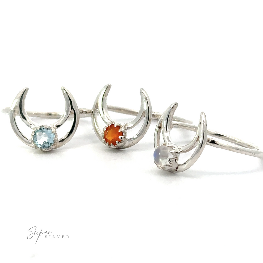 Three Online Exclusive Gemstone Moon Outline Rings designed with crescent moon shapes, each featuring a different colored gemstone.