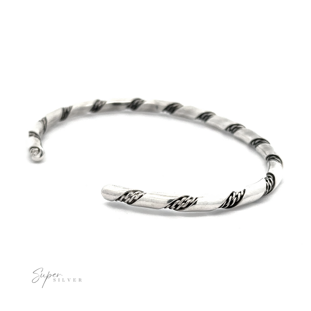 
                  
                    A Native American Handmade Thin Silver Twist Cuff with black rope-like accents, crafted from Sterling Silver, is laid flat on a white background. The logo "Super Silver" is visible in the bottom left corner, showcasing a delicate piece perfect for stacking.
                  
                