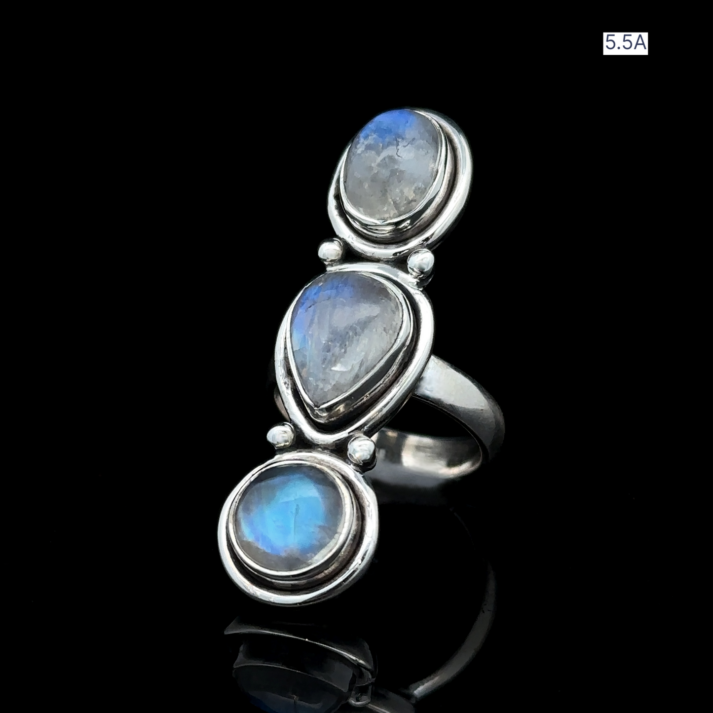 
                  
                    The Triple Moonstone Ring, crafted from sterling silver and featuring three oval moonstones set against a black background, is labeled "5.5A" in the top right corner. Embrace your goddess energy with this exquisite piece.
                  
                