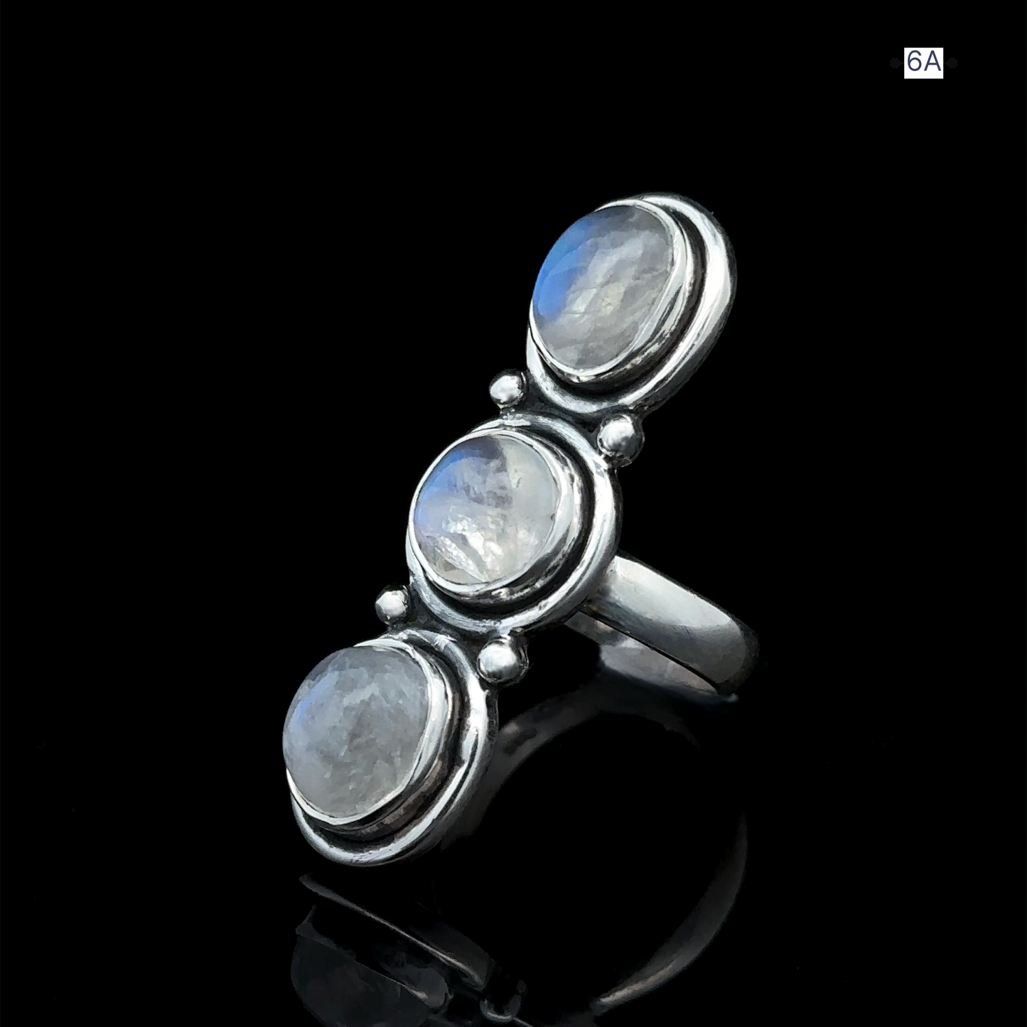 
                  
                    The Triple Moonstone Ring, crafted from sterling silver and featuring three round moonstone gemstones set vertically against a black backdrop, exudes goddess energy.
                  
                