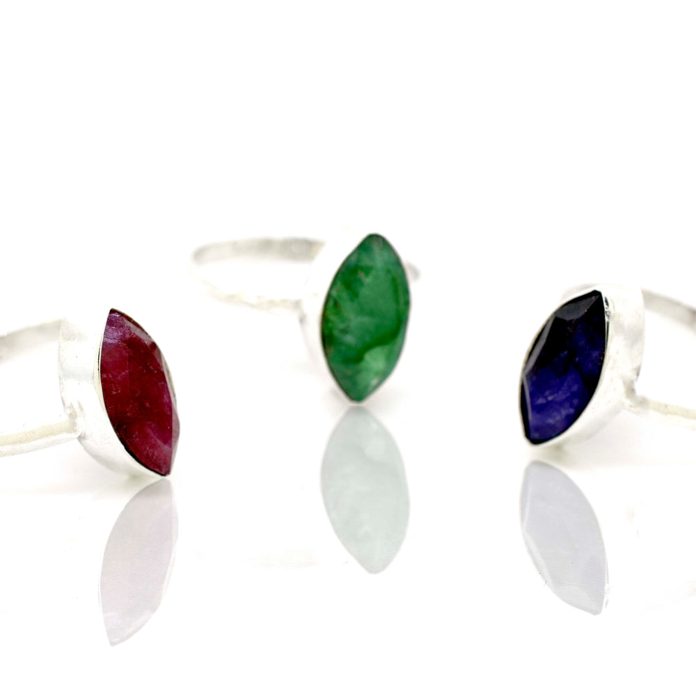
                  
                    Three Simple Marquise Shaped Gemstone Rings with different colored stones on a white surface.
                  
                