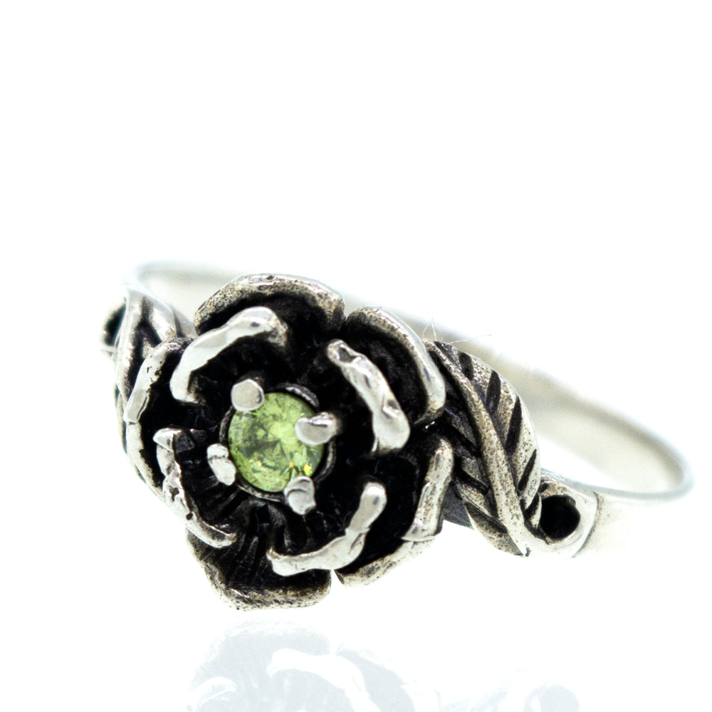 
                  
                    Rose Ring With Cubic Zirconia Stone featuring an intricately designed flower with a small green gemstone at its center.
                  
                