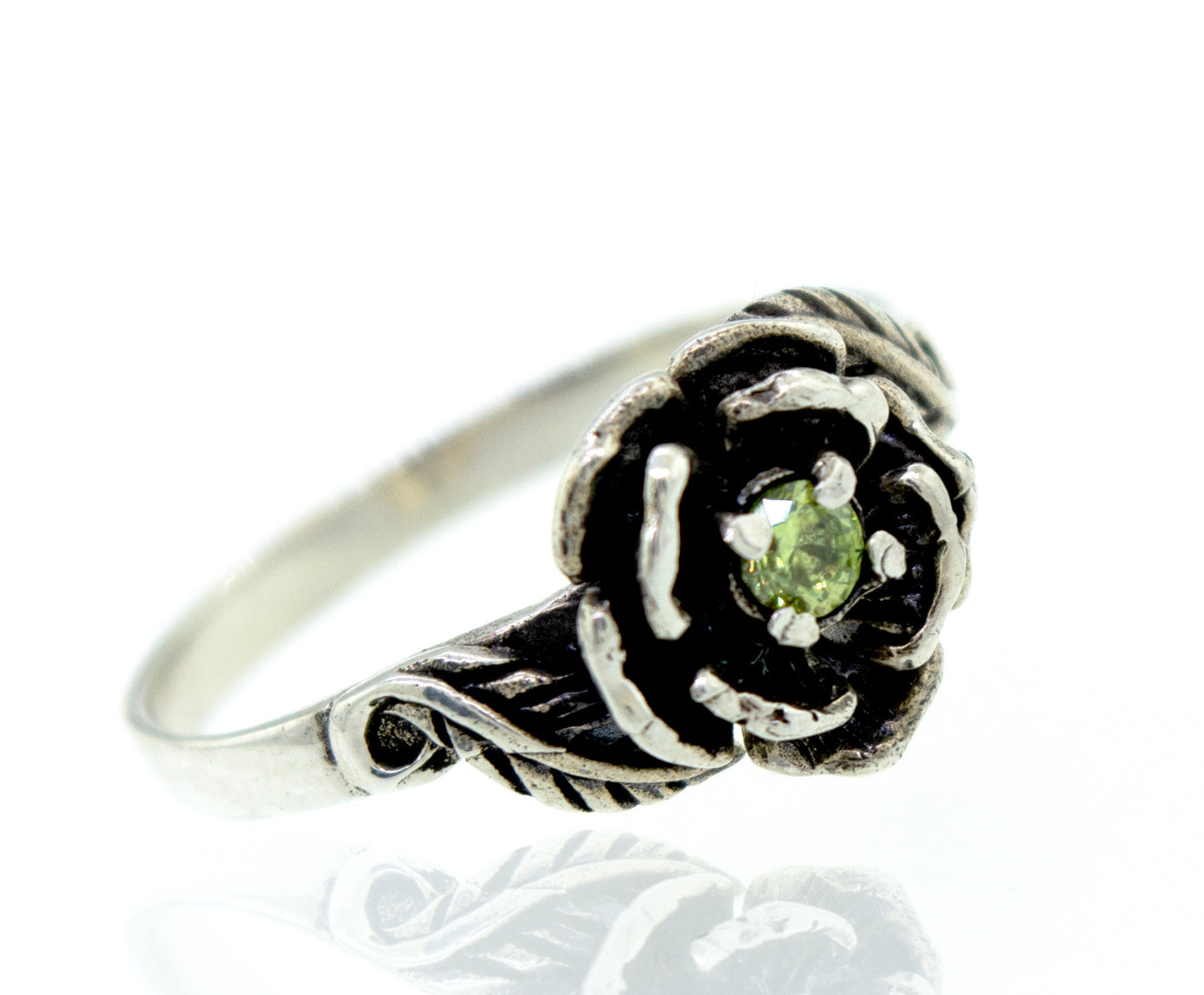 
                  
                    A Rose Ring With Cubic Zirconia Stone featuring a flower-shaped design with a green gemstone at the center, adorned with small stones for an added touch of elegance.
                  
                