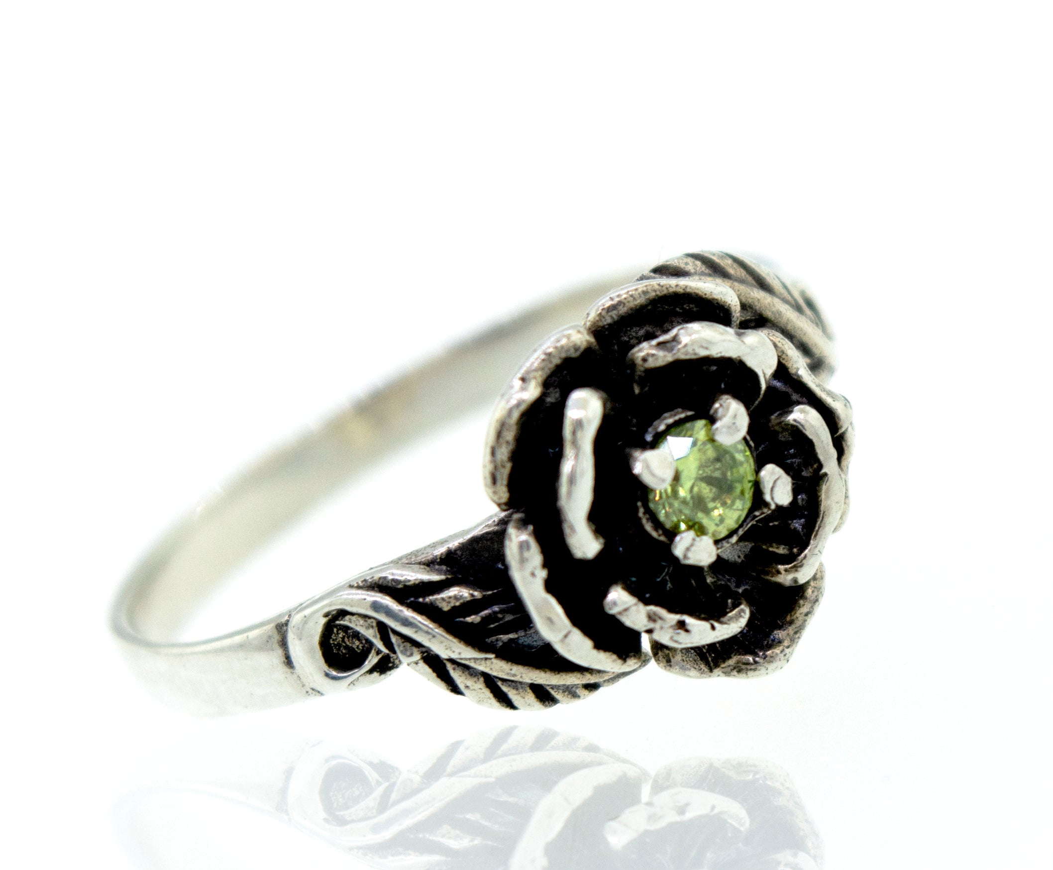A Rose Ring With Cubic Zirconia Stone featuring a flower-shaped design with a green gemstone at the center, adorned with small stones for an added touch of elegance.
