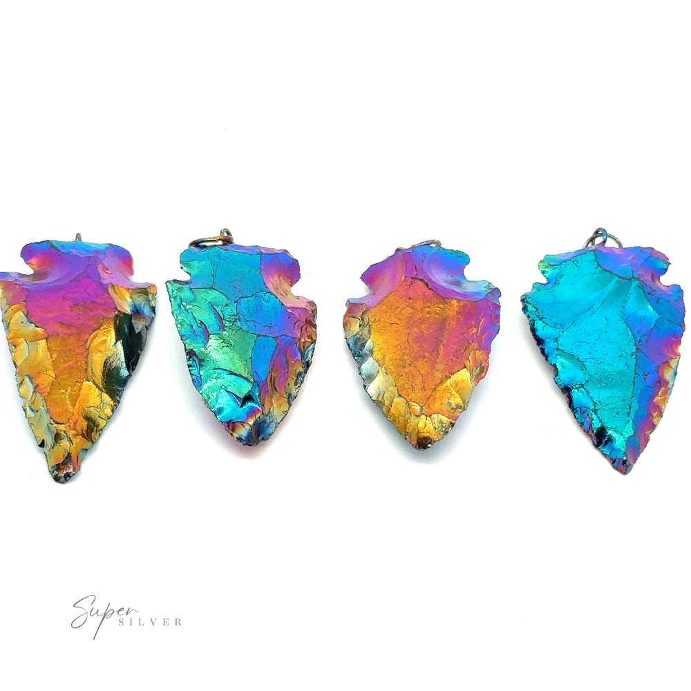 Four Rainbow Hematite Arrowhead Pendants, crafted with mixed metals and featuring iridescent hues, are displayed in a row on a white background.