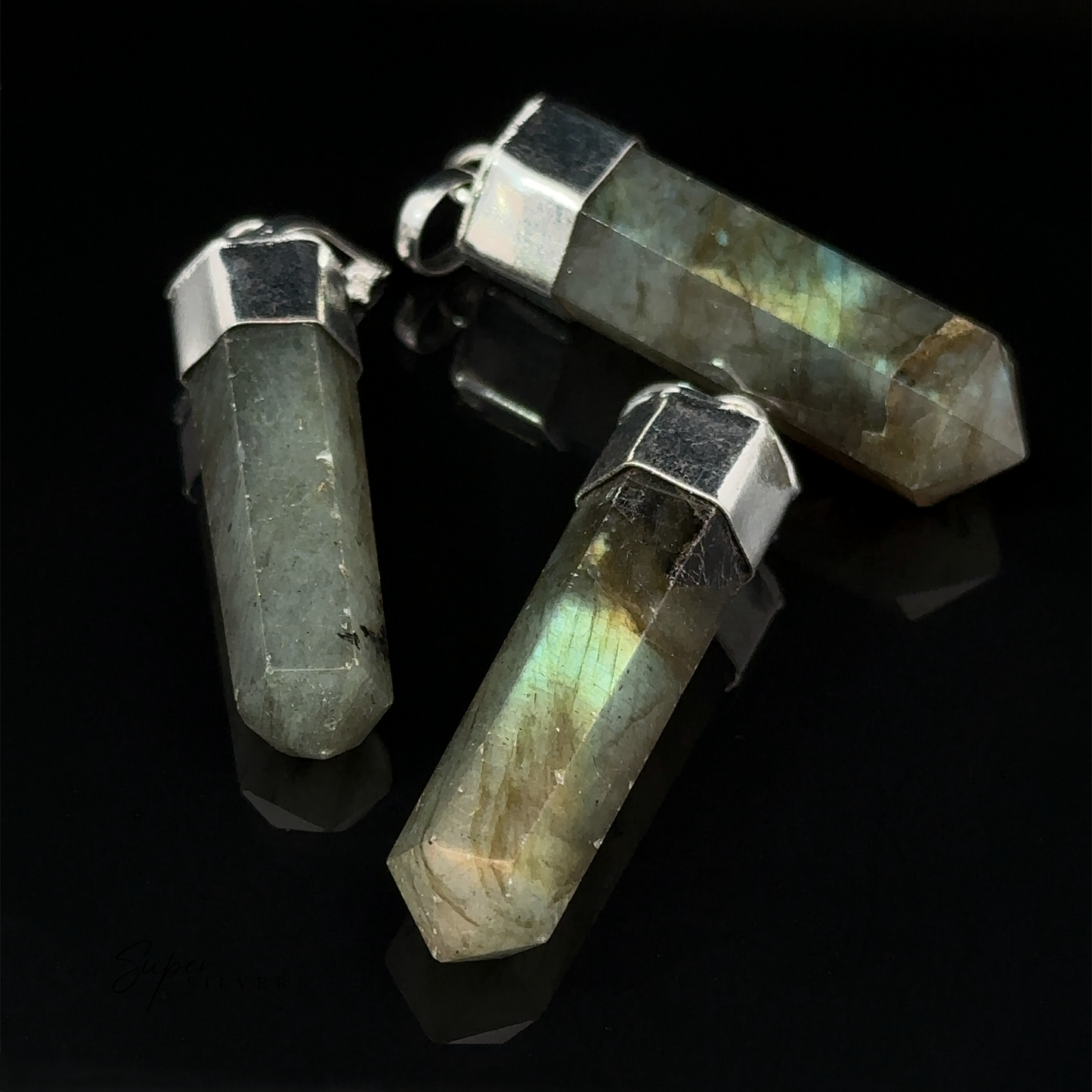 
                  
                    Three Simple Gemstone Point Pendants with silver caps, featuring an earthy design, lay on a black surface.
                  
                
