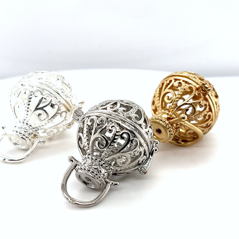 
                  
                    Three Super Silver Filigree Cage Pendants, showcasing precious gems, on a white surface.
                  
                