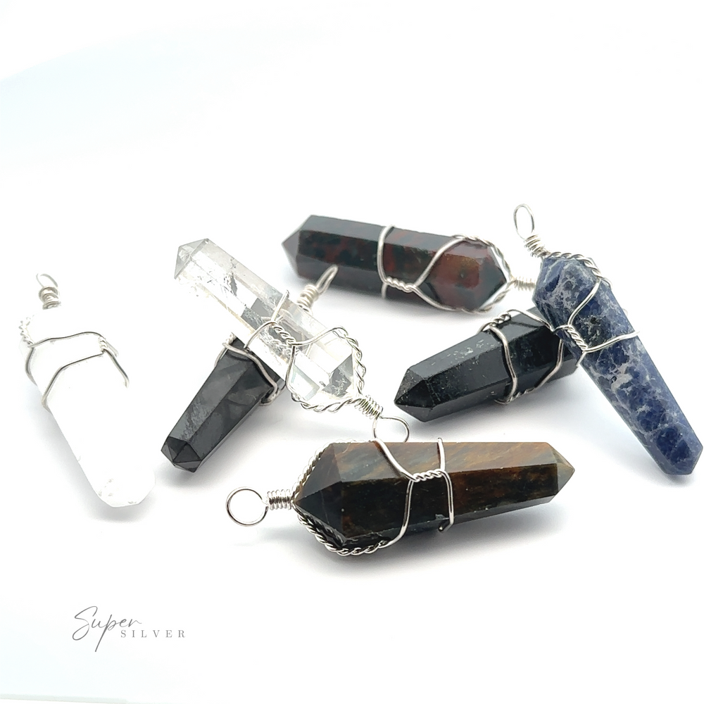 
                  
                    Six Wire Wrapped Stone Pendants with wire wrapping, including clear quartz, black, blue, and multicolored stones like bloodstone, are arranged on a white background.
                  
                