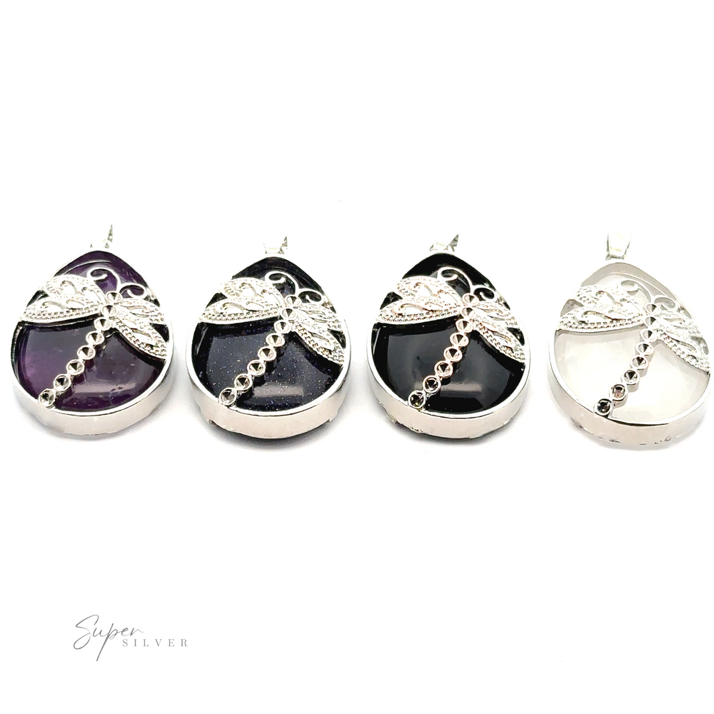 Four Teardrop Stone pendants with Dragonfly, featuring different colored stones (purple amethyst, black, white) and intricate mixed metal detailing, arranged in a row on a white background.