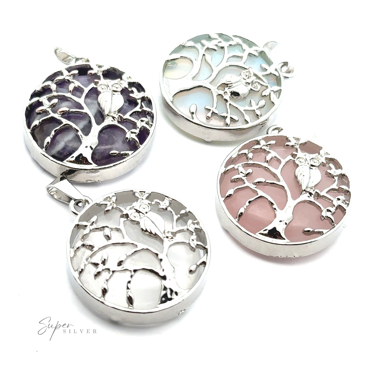 Four Owl and Tree Pendants feature intricate designs with owls perched in their branches. Crafted from mixed metals, each pendant boasts a different colored stone background: Amethyst purple, blue-green, white, and pink.