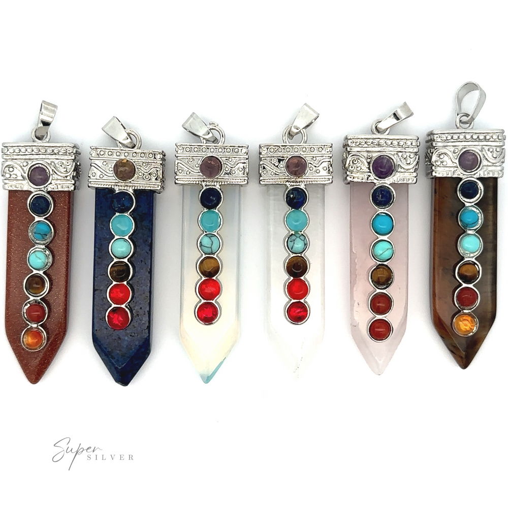 Six pointed crystal pendants, each adorned with seven colorful chakra stones in a vertical line, are displayed against a white background. These stunning Obelisk Crystal Pendant with Small Chakra Stones feature a silver-plated design that adds an extra touch of elegance.