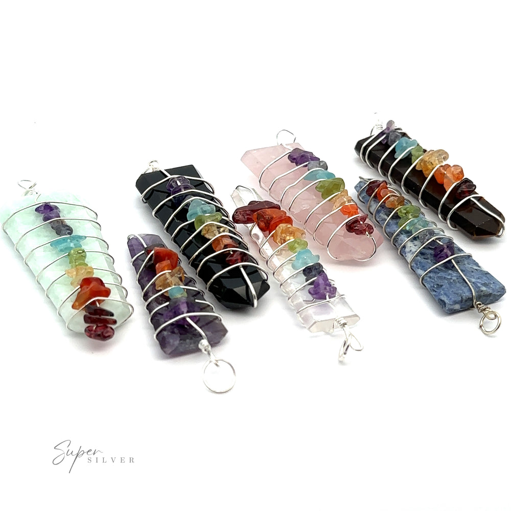 
                  
                    Six Stone Slab Wire-Wrapped Chakra Pendants, each incorporating various colorful chakra stones, are displayed on a white background. The pendants feature silver wire and a small loop for attaching.
                  
                