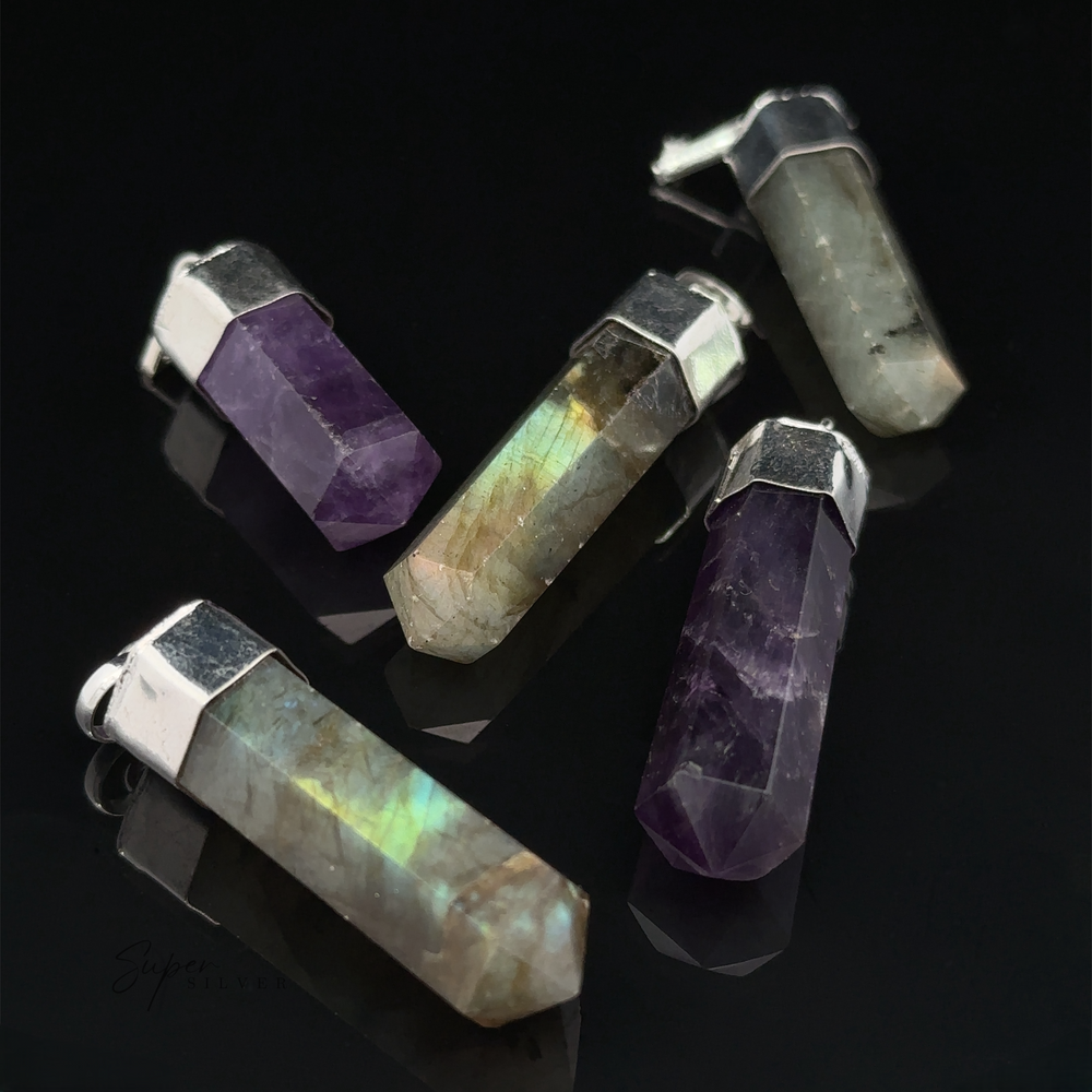 Five Simple Gemstone Point Pendants with silver caps and bails, featuring a mix of labradorite and amethyst, arranged on a black reflective surface. Each crystal pendant showcases an earthy design that complements the natural beauty of the stones.