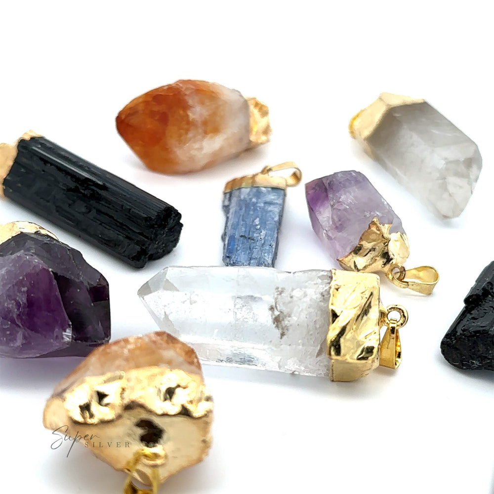 Various Raw Crystal Pendant With Gold Cap, including raw crystal clear quartz, amethyst, black tourmaline, kyanite, and carnelian, arranged on a white background.