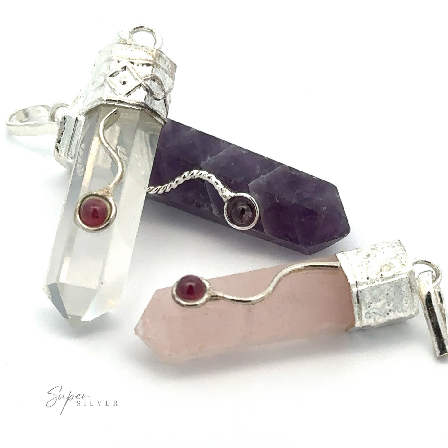 Three Crystal Pendants with Decorative Bail are displayed: one clear, one purple, and one Rose Quartz pink, each with a small red garnet detail embedded in the cap's design.