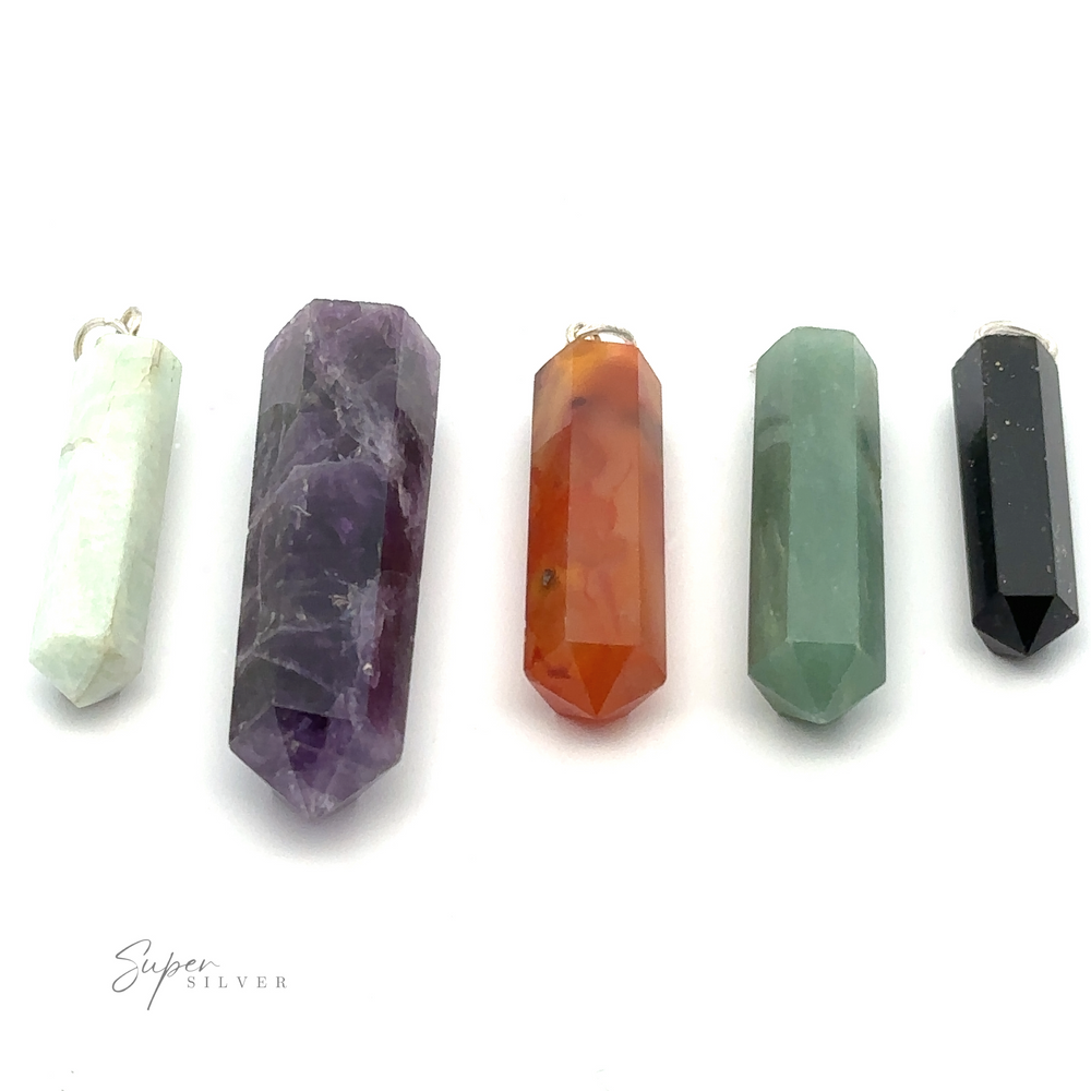 Five hexagonal crystal pendants of varying colors and sizes are arranged in a row against a white background. From left to right, the Raw Stone Obelisk Pendants boast colors of white, purple, orange, green, and black.