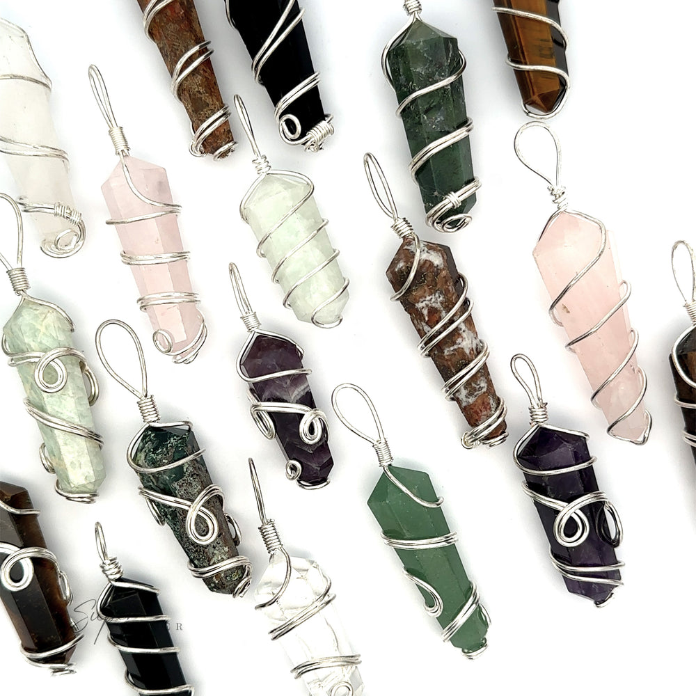 
                  
                    Various Wire Wrapped Stone Pendants are displayed on a white background. These authentic gemstones, available in an array of colors including green, purple, pink, brown, and clear, are elegantly encased in silver wire.
                  
                