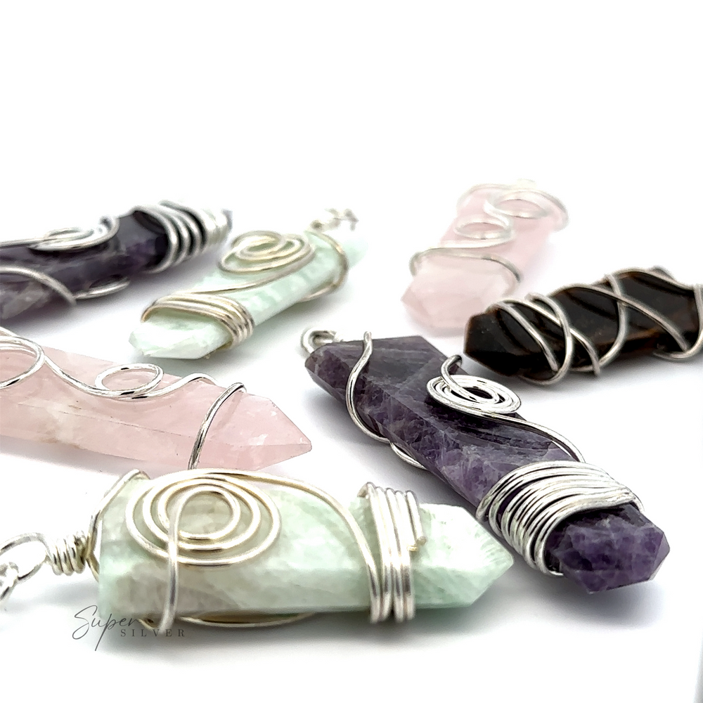 Close-up of various Stone Slab Pendant with Wire Wrapping featuring gemstone pendant stones in different colors including green, pink, purple, and black, arranged on a white background.