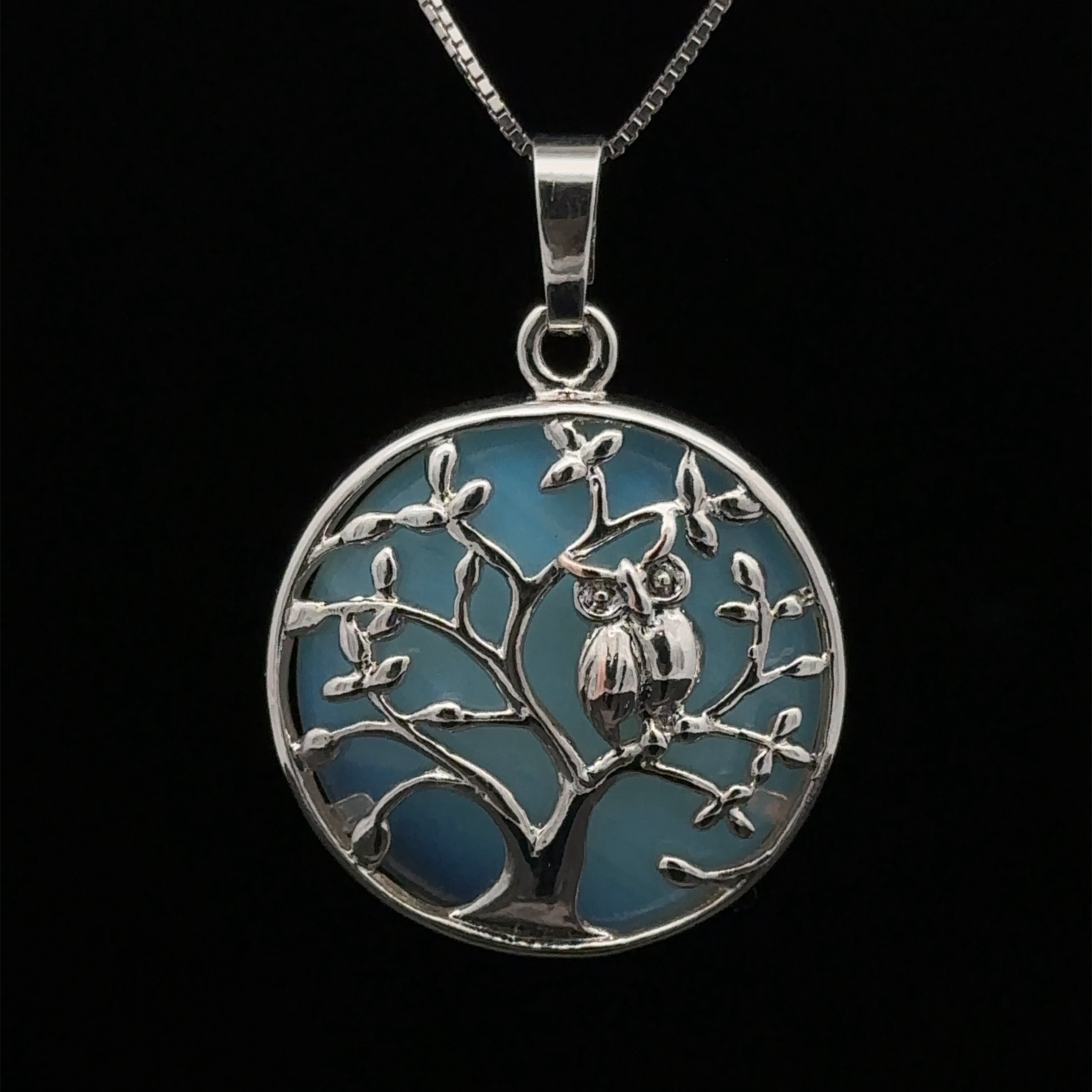 A silver Owl and Tree Pendant featuring a detailed tree with Amethyst accents and two owls perched on a branch against a blue background.