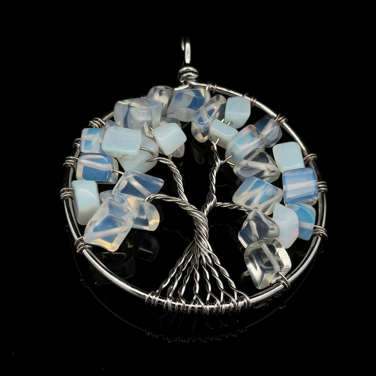 
                  
                    A stunning Wire Wrapped Tree of Life Pendant showcases a silver wire design adorned with blue and white gemstones embedded in the branches, all set against a sleek black background. The piece beautifully integrates mixed metals to create a striking contrast.
                  
                