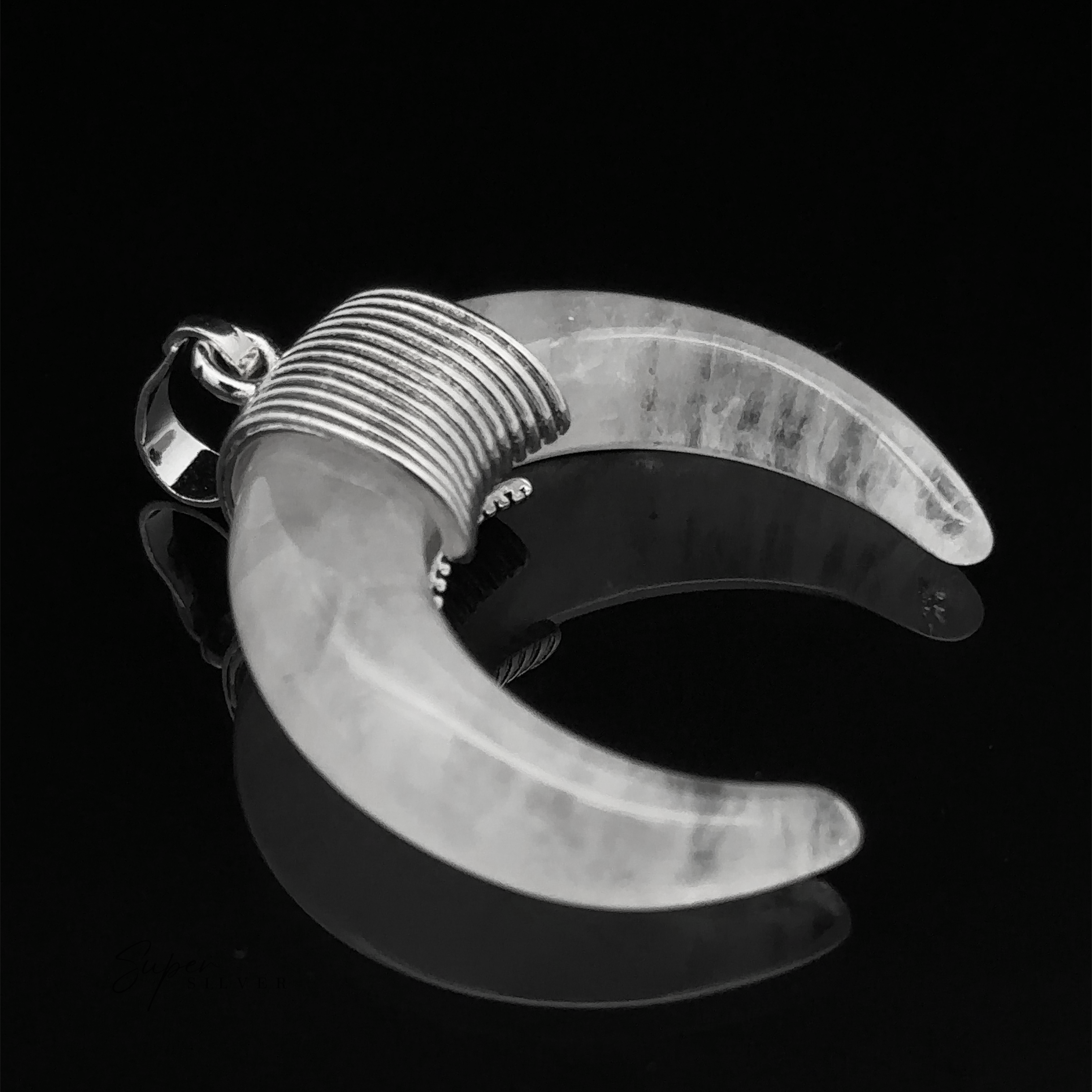 A Naja Stone Pendant with a wire-wrapped design, likely made of mixed metals, lies on a reflective black surface.