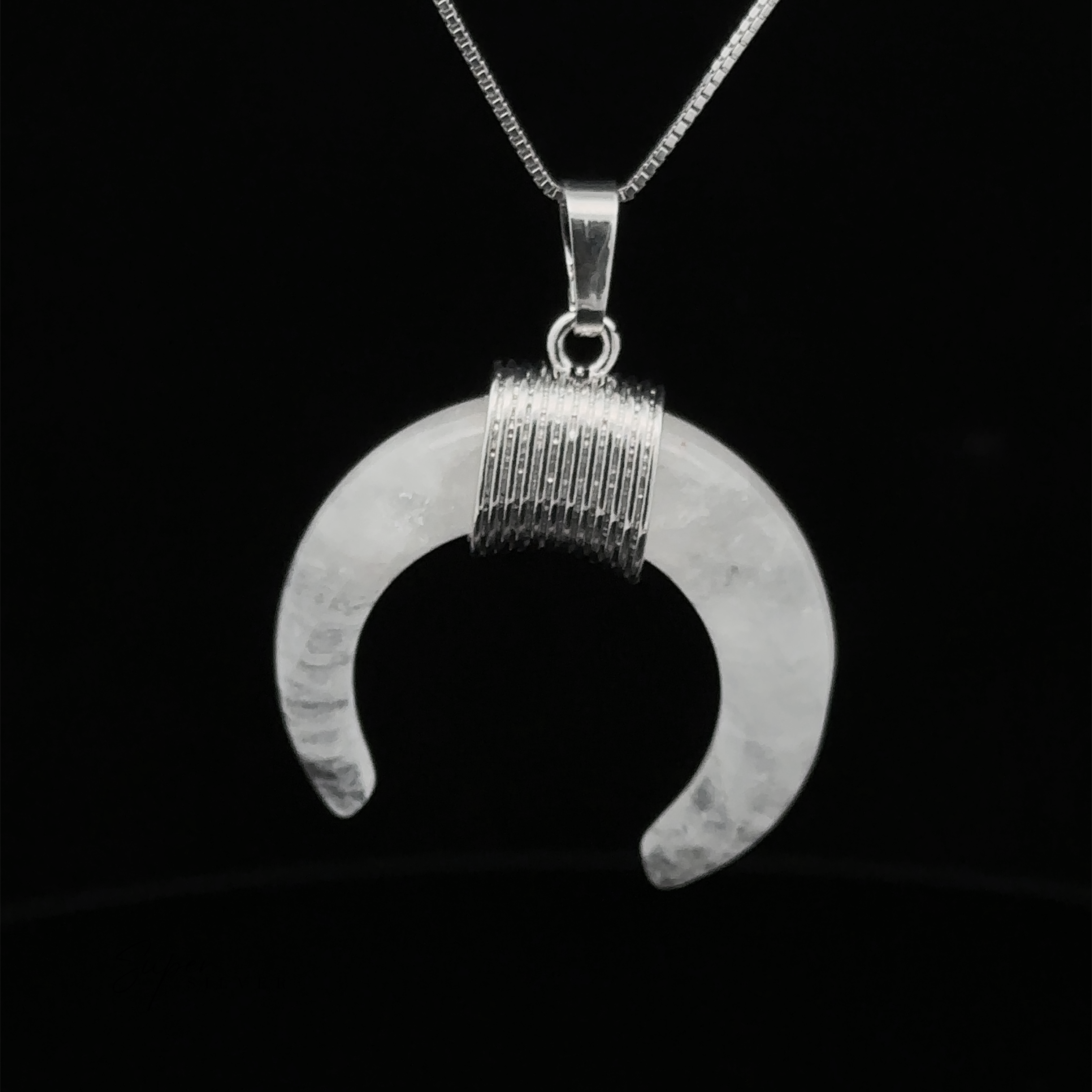 A Naja Stone Pendant featuring a Navajo crescent design hangs from a thin silver chain against a black background, blending traditional craftsmanship with timeless elegance.