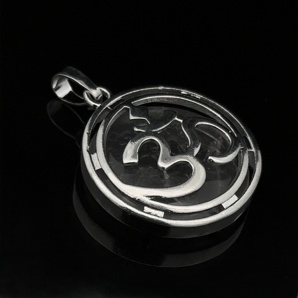 
                  
                    A silver plated Om Pendant with touches of mixed metals, resting elegantly on a black surface.
                  
                