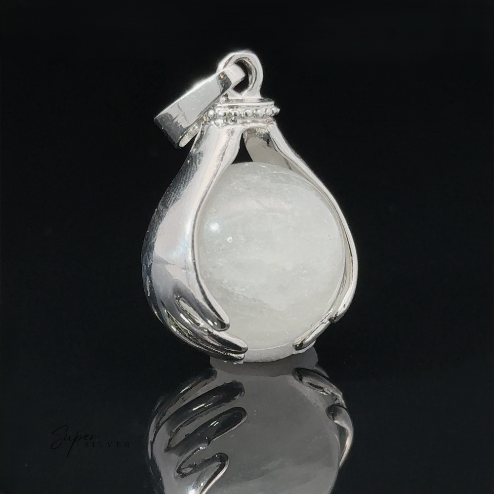 A Sphere Crystal Pendant shaped like two hands holding a round white crystal quartz, shown against a black background with a reflection beneath it.