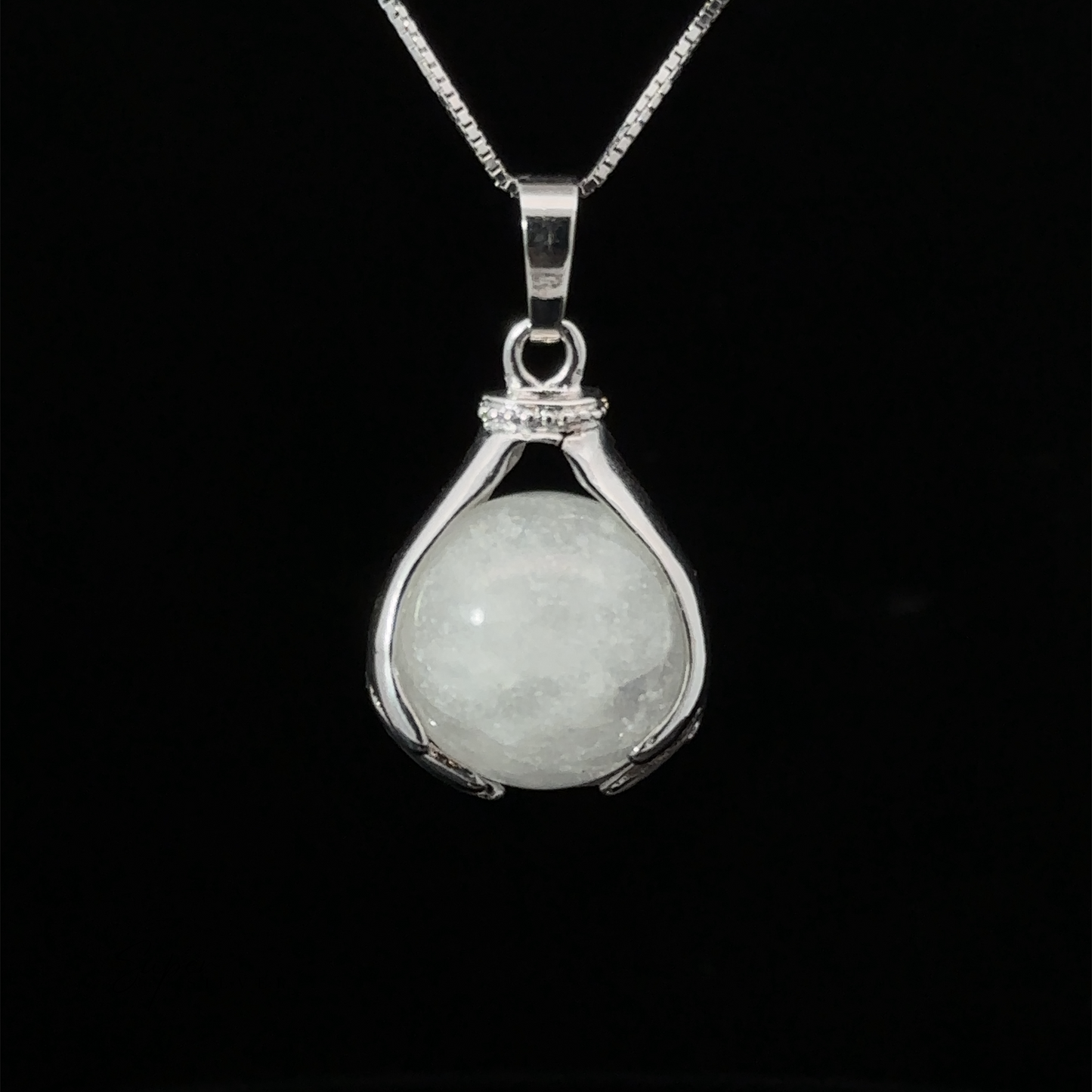 
                  
                    A Sphere Crystal Pendant features a smooth, round quartz gemstone held between two curved prongs, suspended from a thin chain against a black background.
                  
                