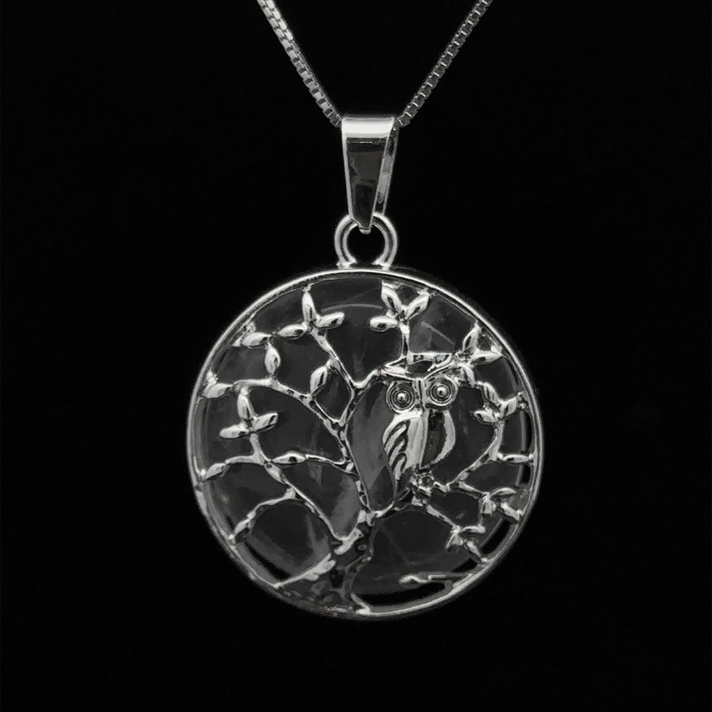 
                  
                    Owl and Tree Pendant featuring an owl perched on a tree branch, with detailed carvings against a black background and an amethyst accent.
                  
                