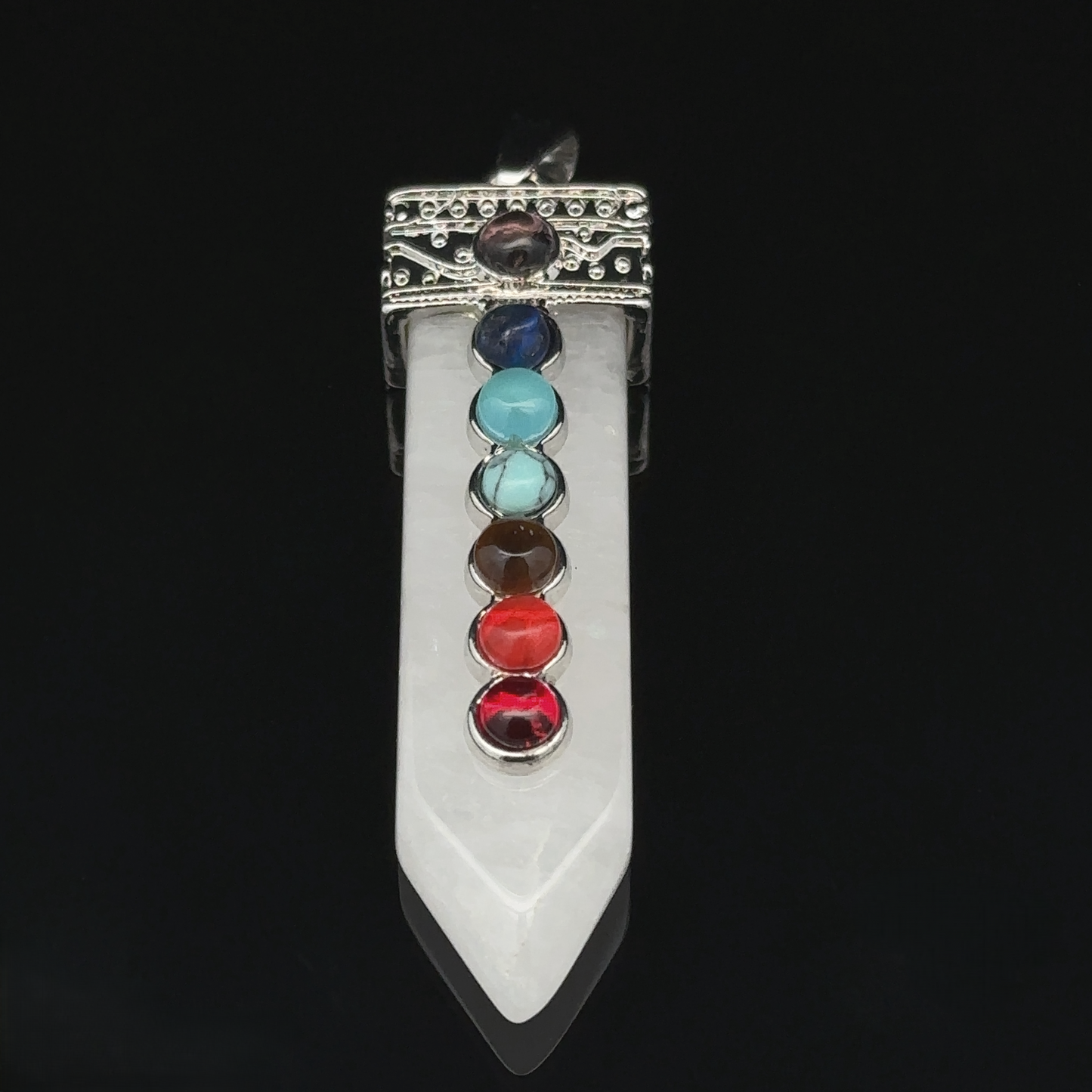 
                  
                    Obelisk Crystal Pendant with Small Chakra Stones featuring a white crystal point, topped with an ornate silver-plated cap featuring seven colored chakra stones arranged in a vertical line, each representing a different energy center.
                  
                