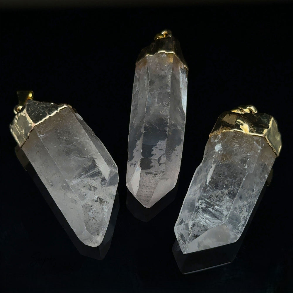 
                  
                    Three Raw Crystal Pendants With Gold Caps are elegantly arranged against a black background.
                  
                