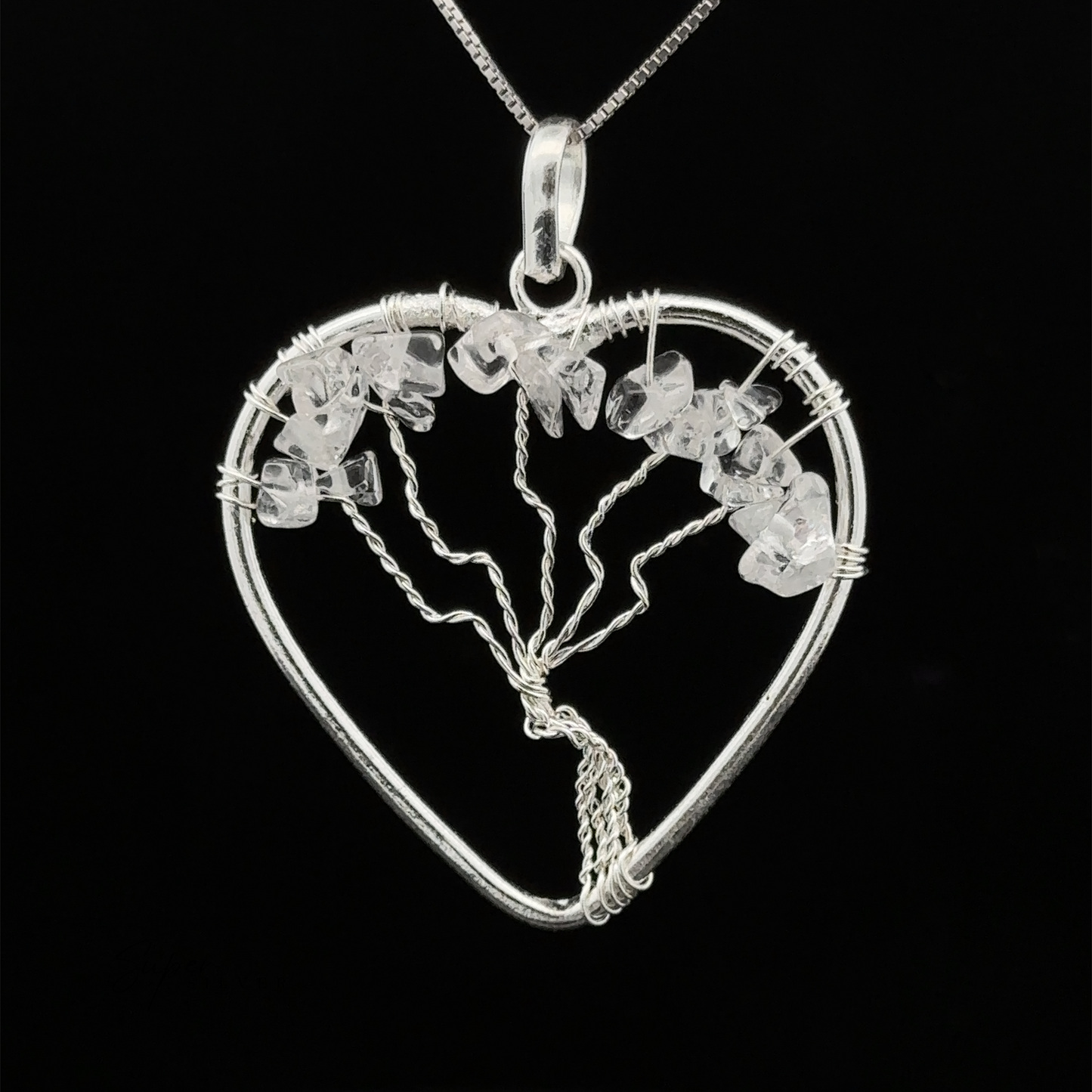 
                  
                    A Heart Shaped Tree of Life Pendant features a wire-wrapped tree design, adorned with small white stones and raw stone beads, all set against a black background.
                  
                