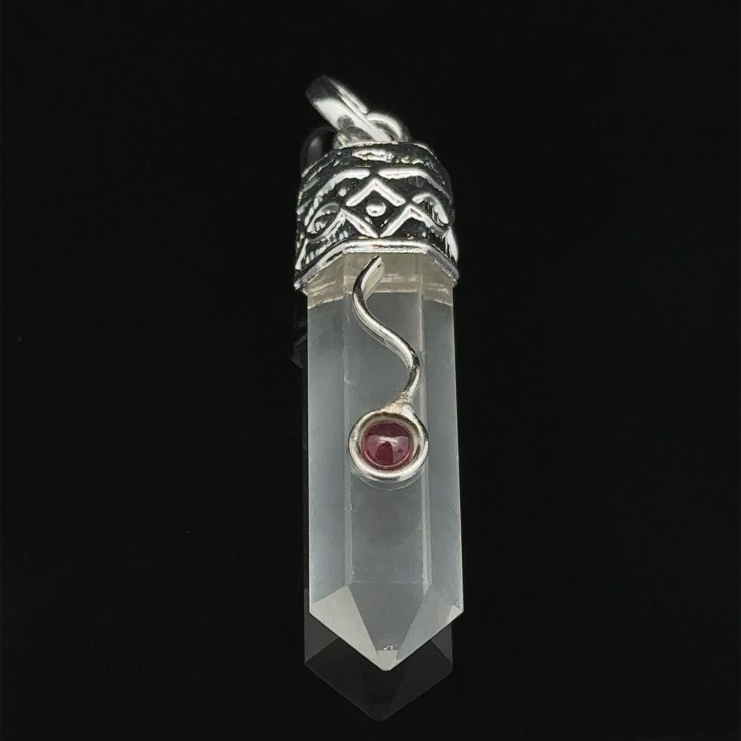 
                  
                    A Crystal Pendant with Decorative Bail with ornate silver details and a small garnet detail set in a curving setting.
                  
                