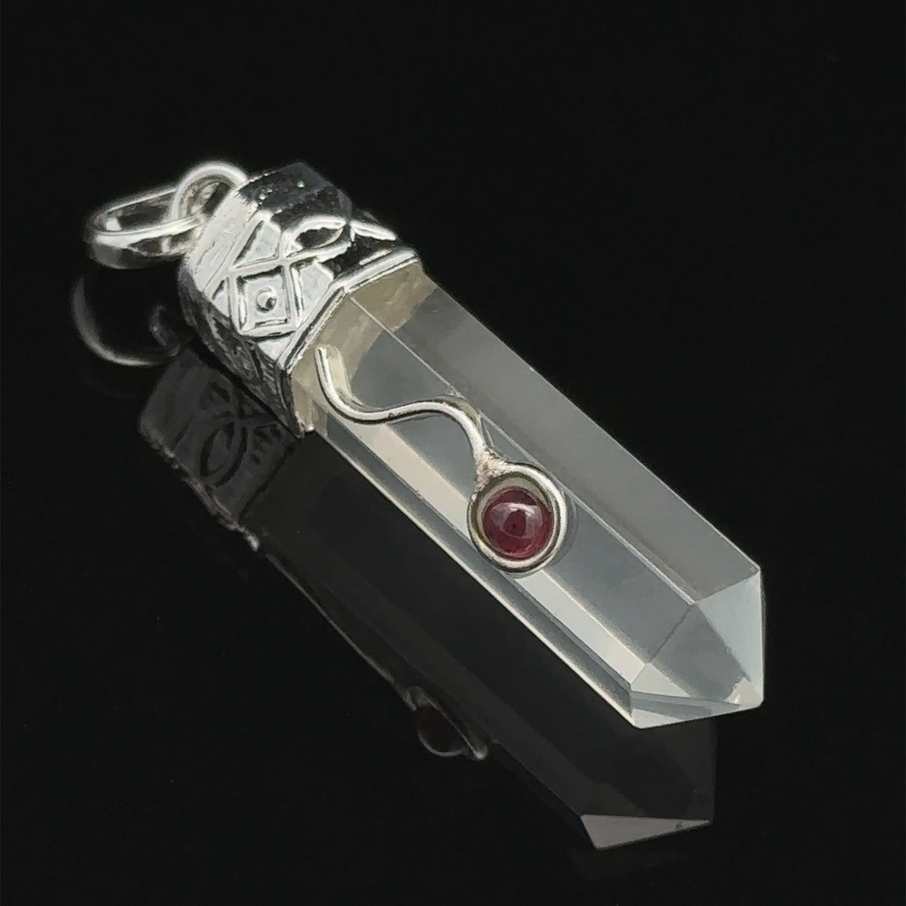 
                  
                    Crystal Pendant with Decorative Bail with a silver cap and a small red stone in the center, resting on a reflective black surface.
                  
                
