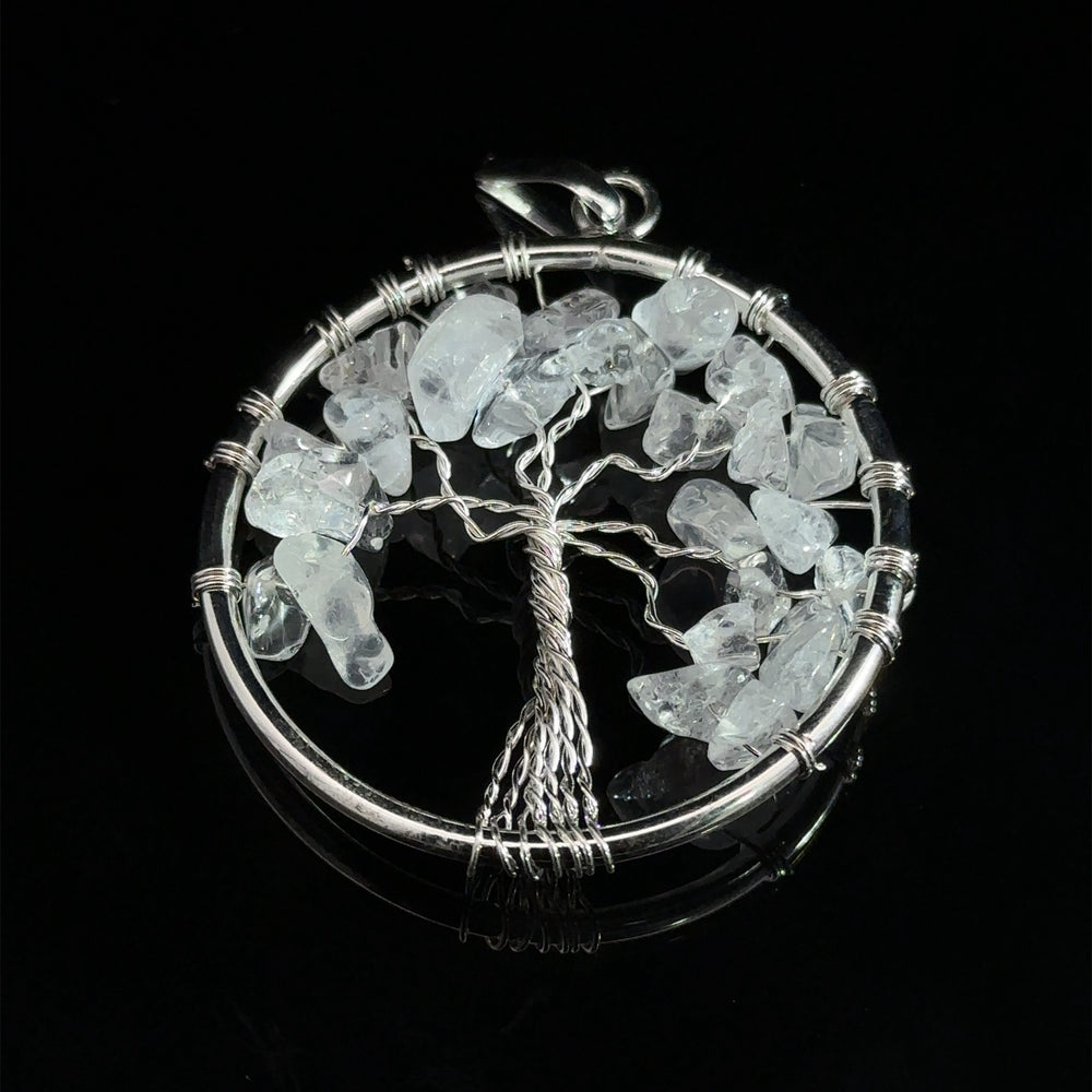 
                  
                    A stunning Wire Wrapped Tree of Life Pendant with Stones showcases a circular design with a wire-wrapped tree at its heart, adorned with translucent gemstones as leaves, all set against a black background.
                  
                