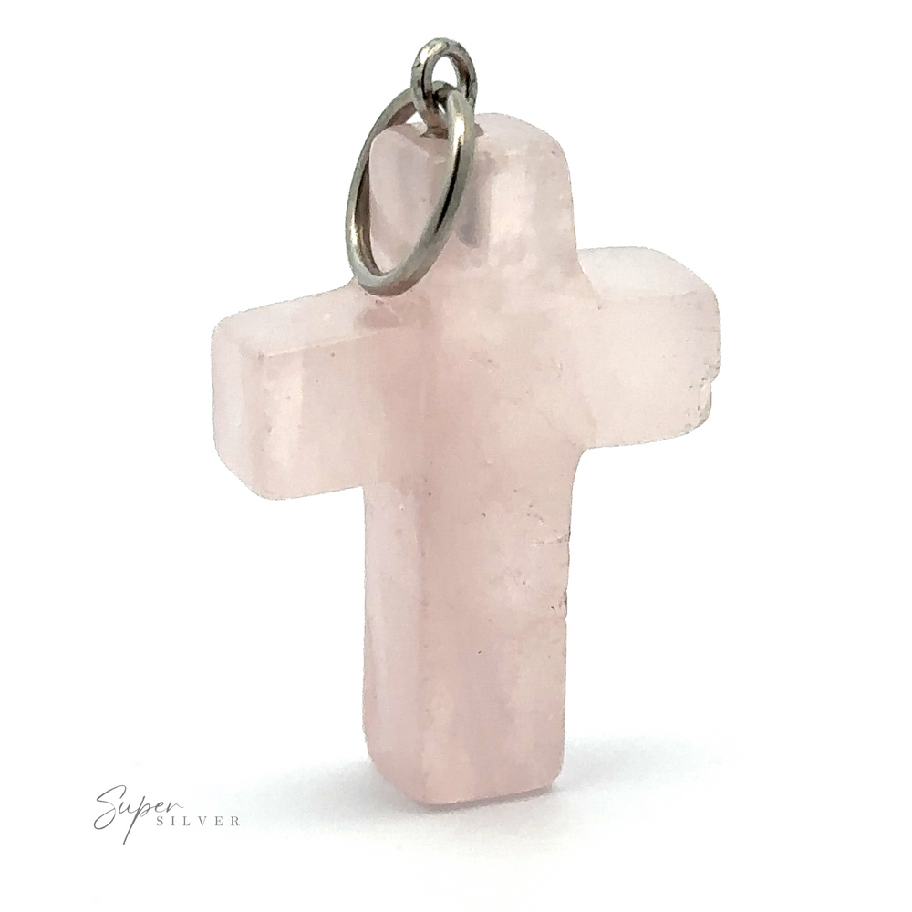 A small, pink Stone Cross Pendant made of rose quartz with a metal loop at the top for attaching to a necklace. The words 